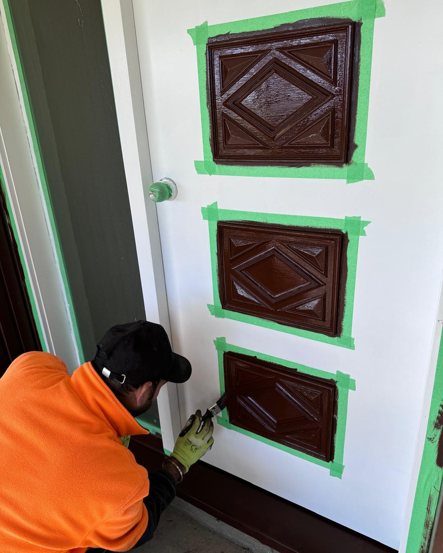 Painter applying fresh coat to door frame during renovation in Auckland